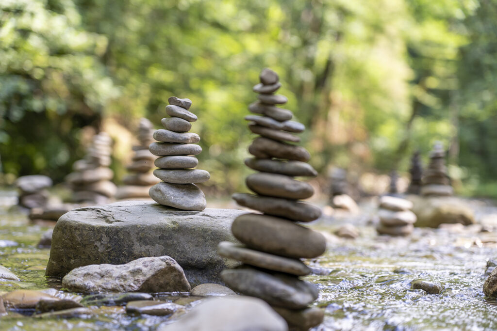 Selective focus shot of many stone pyramids balanced on a river water